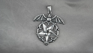 Macro detail of gothic bat and pentagram pendant with vintage oxidized steel finish