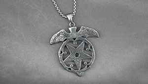 Macro shot of vintage eagle and pentagram pendant on stainless steel box chain