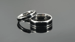 Macro shot of silver polished titanium rings with black brushed center on mirror background