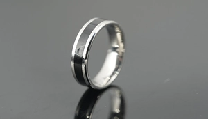 Detail of silver titanium steel ring with black inlay on reflective surface