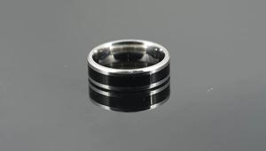 Close-up of polished titanium steel ring with a black inlay on a reflective surface