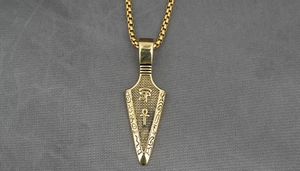 Macro view of gold arrow pendant featuring Eye of Horus and Ankh cross symbols