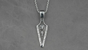 Macro detail of silver arrowhead pendant featuring Egyptian Eye of Horus and Ankh symbols