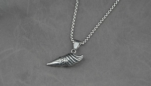 Dettaglio macro del ciondolo a conchiglia in argento vintage con trama a spirale su catena