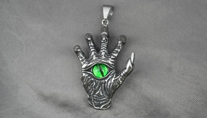 Macro shot of gothic claw pendant with a bright green evil eye and vintage silver finish