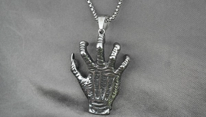 Close-up of stainless steel hand bone pendant with detailed skeleton claw texture