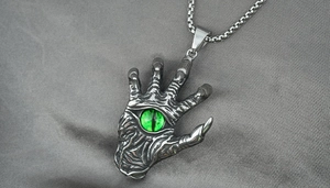 Macro shot of retro silver devil eye palm pendant with green eyeball and steel box chain