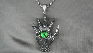 Macro shot of gothic claw pendant with green evil eye and vintage stainless steel finish