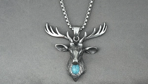 Détail d'un pendentif tête de cerf vintage avec pierre turquoise sur chaîne en acier