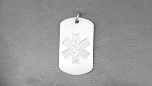 Macro shot of stainless steel medical alert tag with engraved Star of Life and caduceus symbol