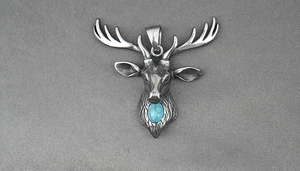 Détail d'un pendentif tête de cerf argenté vintage avec pierre turquoise bleue