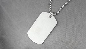 Macro detail of silver dog tag pendant with brushed matte finish on box chain