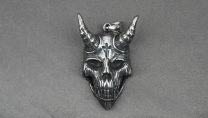 Detailed macro view of vintage silver devil skull pendant with horns and cross engraving