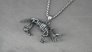 Detailed macro shot of vintage silver Triceratops skeleton pendant on dark box chain