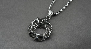 Vue détaillée du pendentif dragon en argent vieilli sur un fond en tissu texturé gris