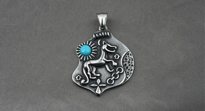 Detailed close-up of a vintage dog pendant with turquoise inlay on textured grey fabric