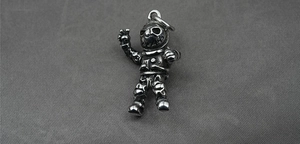Detail of silver vintage astronaut pendant with peace sign gesture on gray textured cloth