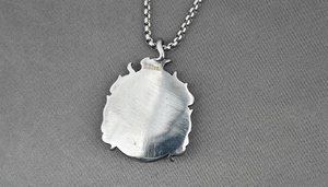 Dettaglio macro del ciondolo a fiamma in acciaio inossidabile argento con incisione S.Steel