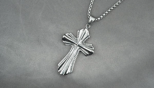 Detail view of silver cross pendant with radial grooves and steel box chain