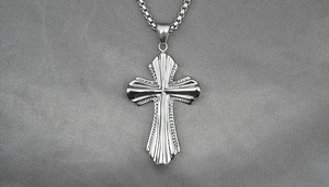 Detail of silver titanium steel cross pendant necklace with textured radiant pattern