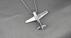 Détail macro du dos du pendentif avion en argent avec gravure STEEL et chaîne à maillons