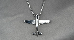 Détail d'un collier pendentif avion argenté avec une chaîne élégante sur velours gris