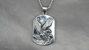 Nahaufnahme von Adler-Reliefanhänger mit Gebirgsszene und quadratischer Box-Kette