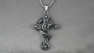 Macro view of gothic dragon pendant with cross and skull on textured background