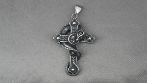 Macro shot of gothic steel cross pendant featuring scaled dragon and skull detail
