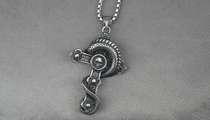 Detailed macro of vintage dragon cross pendant with skull motif in antique silver finish
