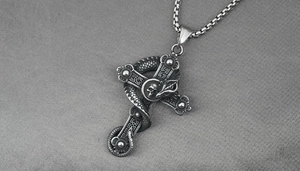 Macro shot of gothic dragon cross necklace with skull detail on dark satin fabric