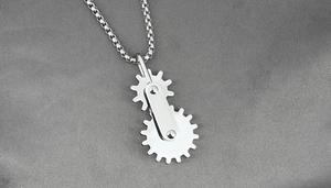Close-up of polished stainless steel rotating gear pendant on a silver box chain necklace