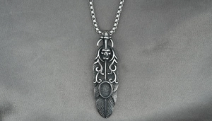 Détail du pendentif plume gothique avec gravure de crâne sur une chaîne en acier vintage
