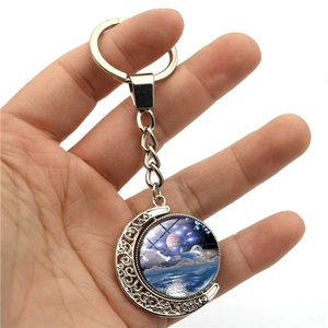 Handheld silver rotating moon keychain with galaxy starry glass ball and ornate hollow carvings