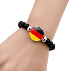 Detail of matte black beaded bracelet with Germany flag glass charm on a wrist