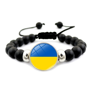 Detail of beaded bracelet with black matte beads and Ukraine flag charm on white background