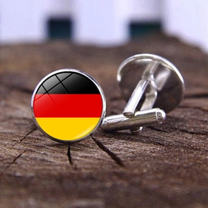 Macro shot of German flag cufflinks with glass dome on a textured wooden background