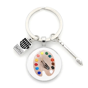 Detailed view of art-themed keychain with colorful palette, crayons, and silver paintbrush
