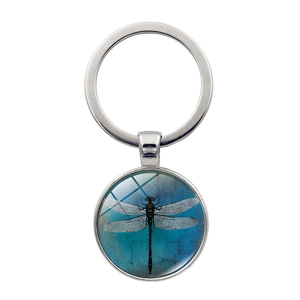 Macro detail of retro dragonfly art pendant with clear glass cabochon on metal keychain