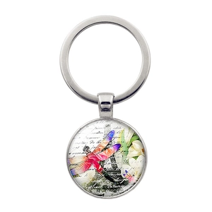 Detail of vintage silver keychain with dragonfly and Eiffel Tower motif under glass