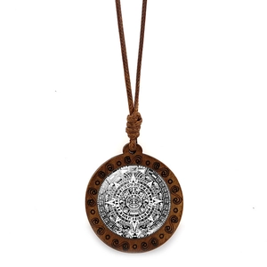 Détail rapproché du motif du calendrier aztèque sur un pendentif rond en bois et cordon