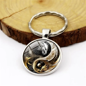 Yin Yang Dragon Tai Chi metal keychain with glass dome pendant on a wooden background