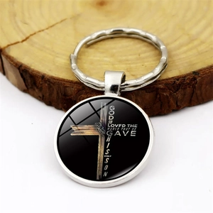 Christian cross glass dome keychain with John 3:16 Bible verse on wooden background