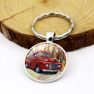 Vintage red truck keychain with round glass pendant on wood background texture