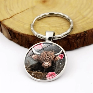 Artistic silver alloy Highland Cow keychain with pink flowers on a circular glass pendant