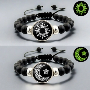 Détail des breloques lumineuses soleil et lune sur des bracelets en perles noires mates