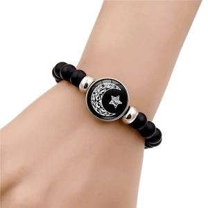 Gros plan d'un bracelet en perles noires mates avec un pendentif lune et étoiles au poignet
