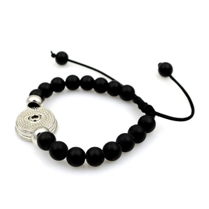 Détails des perles noires mates et de l'attache argentée sur le bracelet réglable tissé