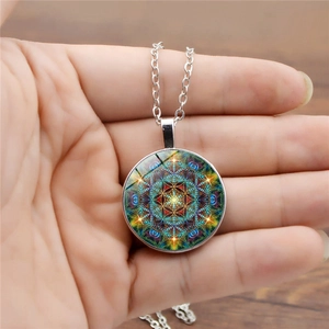 Gros plan d'un collier pendentif mandala en verre tenu à la main pour l'échelle