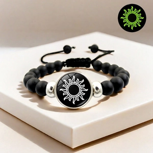 Détail macro du charme soleil sur bracelet de perles noires mates à effet lumineux